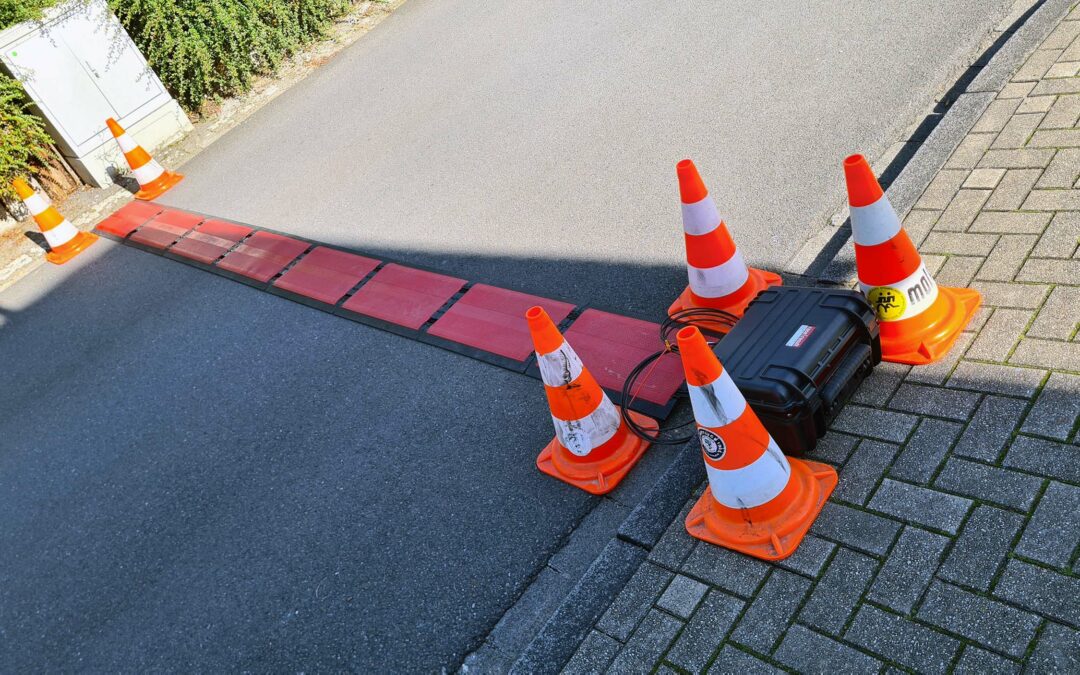 Bild einer BAS-Antenne auf der Straße und einer Raceresult-Decoderbox am Straßenrand, die Decoderbox ist mit 4 orangefarbene Pylonen gesichert