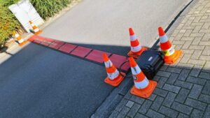 Bild einer BAS-Antenne auf der Straße und einer Raceresult-Decoderbox am Straßenrand, die Decoderbox ist mit 4 orangefarbene Pylonen gesichert